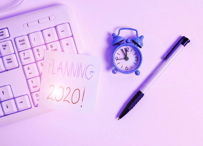 显示2020年规划的文字标志。概念照片计划明年某物的过程白色电脑键盘，白色背景上有空白便笺。