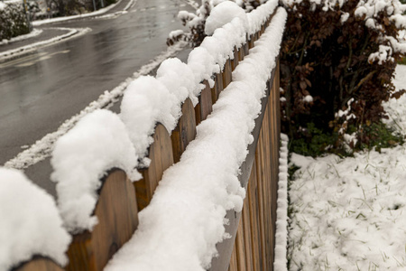 泥泞的路上挂着雪冠的木栅栏图片