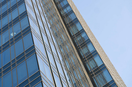 天空在建筑物窗户上的倒影。蓝天上现代玻璃建筑摩天大楼的透视和俯视。商务办公楼或公司大楼的窗户。