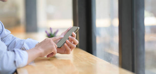 Cropped shot of young businessman using his smartphone in modern