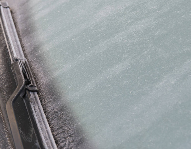 冬季结冰的挡风玻璃特写照片和汽车雨刮器。冻结的