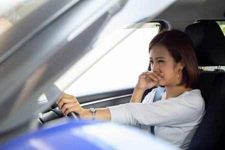 年轻的亚洲女人因为车里有臭味而捂着鼻子