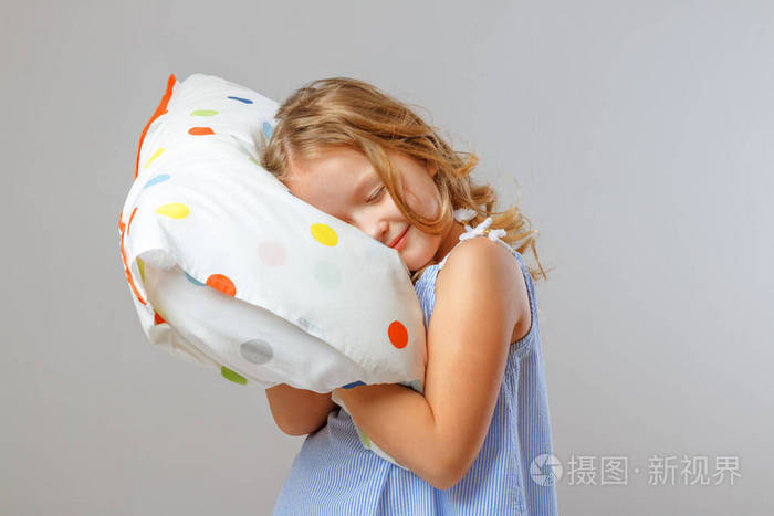 人与健康睡眠理念一个小女孩抱着一个柔软的枕头闭上眼睛在摄影棚的
