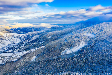 白雪皑皑的森林覆盖着晴天的群山，空中景观。假日旅游概念