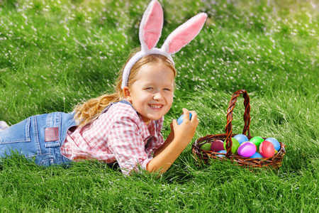 一个可爱的小女孩在花园里收集复活节彩蛋