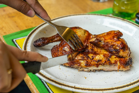 吃烤鸡时用刀叉的人的手照片