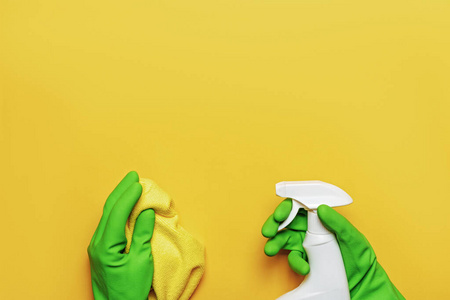 工人手戴橡胶防护手套，黄色背景上有餐巾和喷雾瓶。清洁，照顾房子的概念
