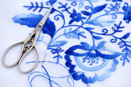 Embroidery, scissors, sewing needle and thread.