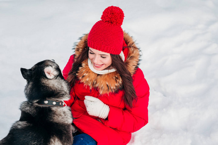 迷人的年轻女子在雪地里和她的狗玩耍