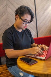 亚裔女同性恋在自助餐厅使用笔记本电脑和智能手机的肖像