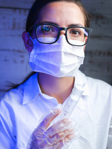 戴着黑眼镜的女医生拿着注射器。脸上缠着白色绷带。助理特写