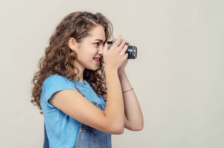 翘臀一个卷曲的黑发女孩穿着牛仔工作服,手里拿着一台老式胶卷相机