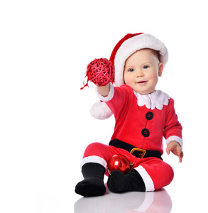 小男孩蹒跚学步的圣诞老人服装和帽子高兴的微笑着红色礼品球杉木装饰准备庆祝