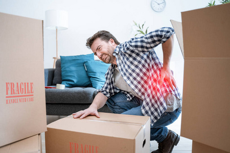 男人搬箱子,因为体重太重而感到背痛照片