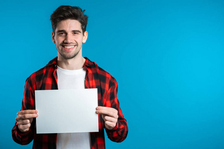 复制空间.穿着蓝色背景的红色格子衬衫微笑的时髦男人.照片