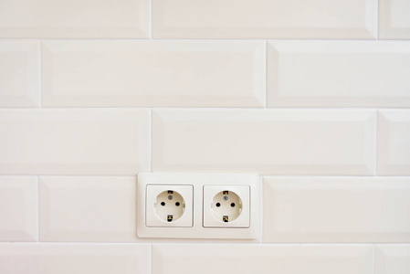 两个电源插座。米色墙壁上的两个类似砖块的米色插座