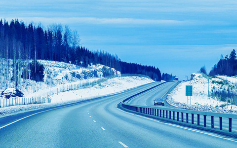 冬季道路上的汽车有雪在芬兰反射