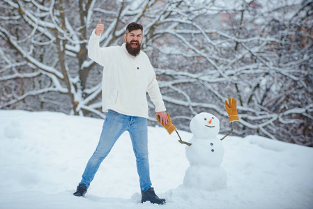 快乐的爸爸在雪地里和雪人玩耍。白雪背景上的圣诞老人和雪人。为人类制造雪人和冬天的乐趣。