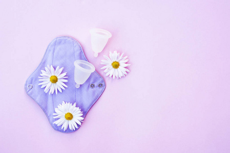 Reusable pad and menstrual cup with daisies on pink fogn. 