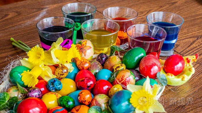 装饰精美的盘子，上面有复活节彩蛋鲜花和五颜六色的彩绘玻璃杯。