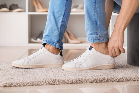 在胶鞋鞋在家穿鞋子的年轻人照片