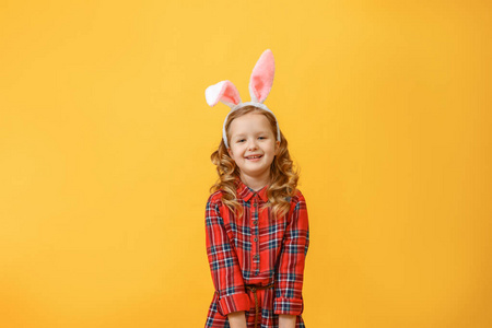 一个可爱的小女孩的肖像，在彩色背景上有一对兔子耳朵。复活节快乐