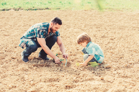 地球日快乐。家谱。父子俩在地上种花。小男孩帮助父亲耕作。地球日。新生活。土壤肥料。天然土壤肥沃。生态农场。有爱心的园丁