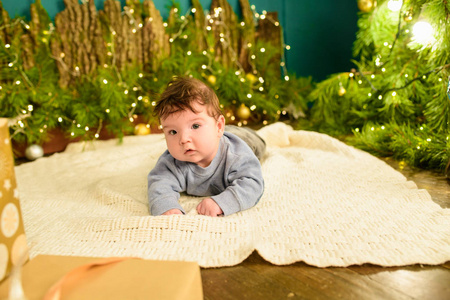 一个孩子在圣诞树旁。小男孩庆祝圣诞节。宝宝的第一个圣诞节。