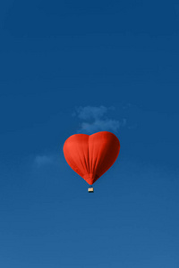 蓝色天空衬托下心形的红色气球