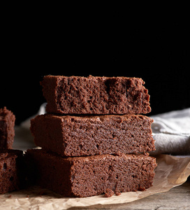 stack of baked square pieces of chocolate brownie cake on brown 