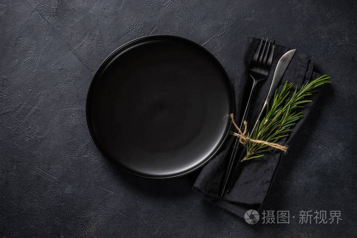 白色盘子，餐具和餐巾在黑色桌面视图。