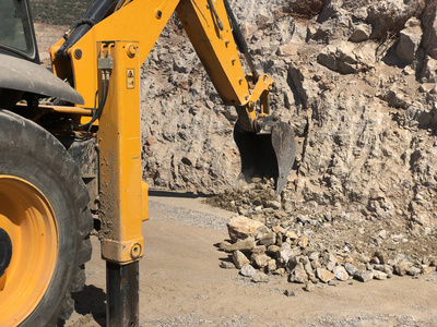 在道路建设工程中，黄色装载机反铲挖沟。运土挖掘在岩石土壤上挖掘