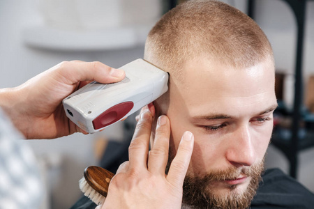 理发师用电动剃须刀给留胡子的客户剃头