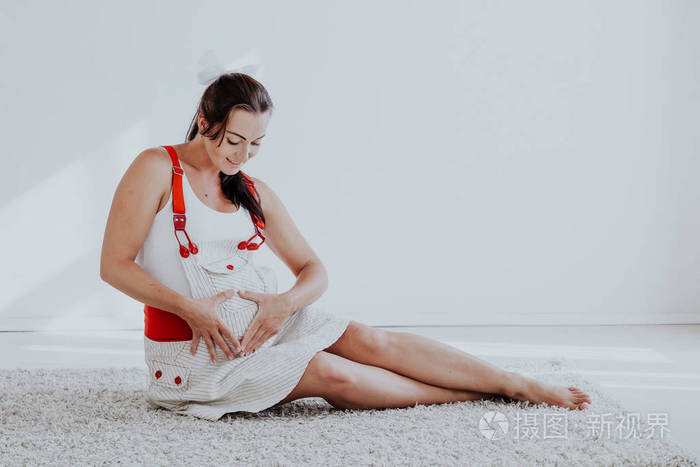 一个孕妇坐在地板上和肚子里的婴儿说话