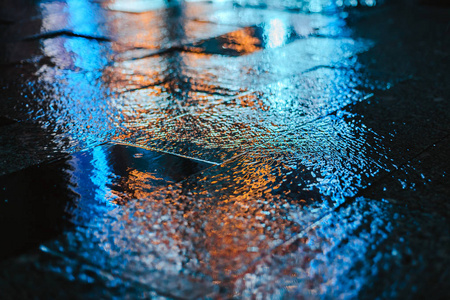 大城市的雨夜，潮湿路面上灯光的倒影。