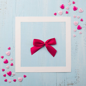 手工制作的红色蝴蝶结和粉色小心形，背景为木质蓝色