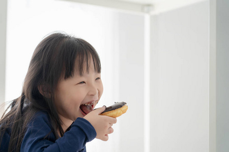 饥饿美丽的亚洲女孩吃巧克力的特写脸