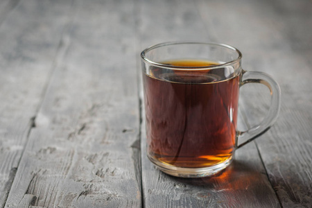 Glass mug with herbal drink on a black rustic table. 