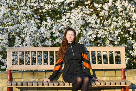 girl on the background of a blossoming apple tree. in black clot