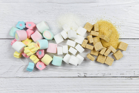 White sugar , sugar cubes and colorful candy sweet on the table 