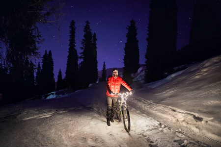 Man with bicycle at winter forest at night 