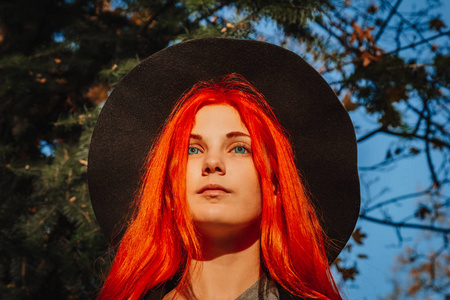 性感美丽的红发女孩,一头浓密的长发,戴着黑色的帽子和外套.