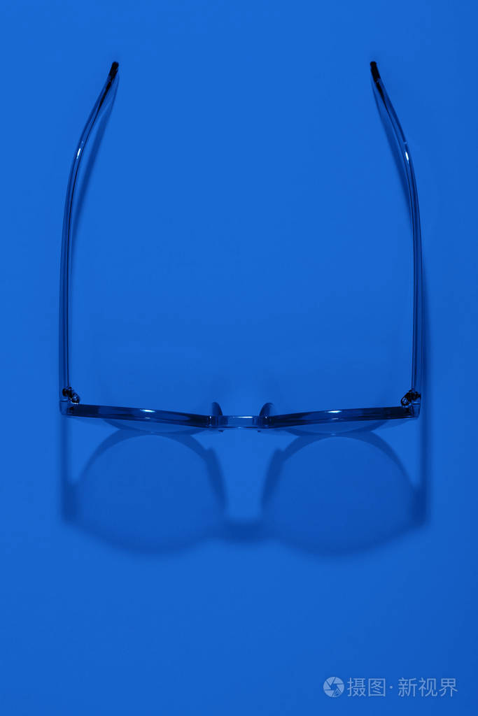 时尚的蓝色眼镜在明亮的背景上有阴影