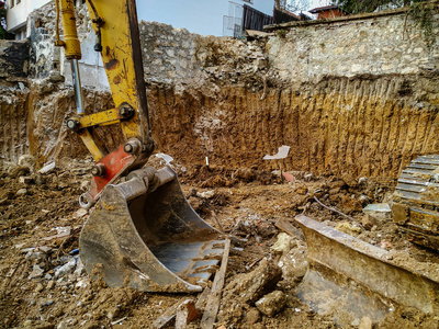 在施工现场挖掘时，巨大的推土机铲头在挖掘现场的泥土中工作