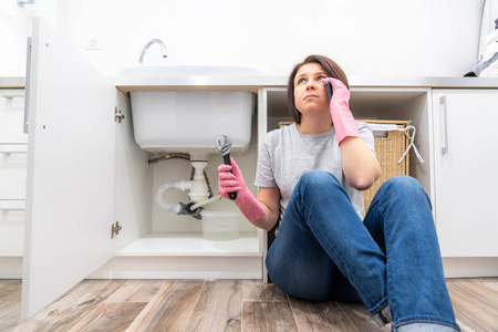 一名妇女坐在洗衣房漏水的水槽旁呼救