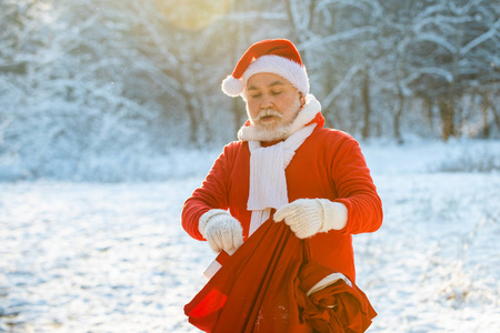 冬天,圣诞老人带着一袋礼物走在雪地上.圣诞快乐.