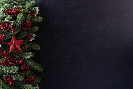 圣诞背景概念。圣诞礼品盒的俯视图红色球云杉树枝，松果，红色浆果和铃铛在黑色木质背景。