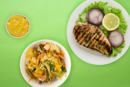  grilled chicken with vegetables lemon, salad, onion on a color