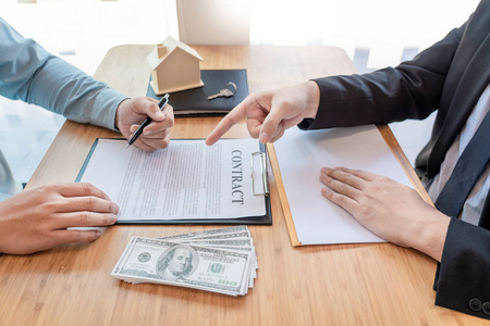 商人在住宅建筑模型后面签合同照片