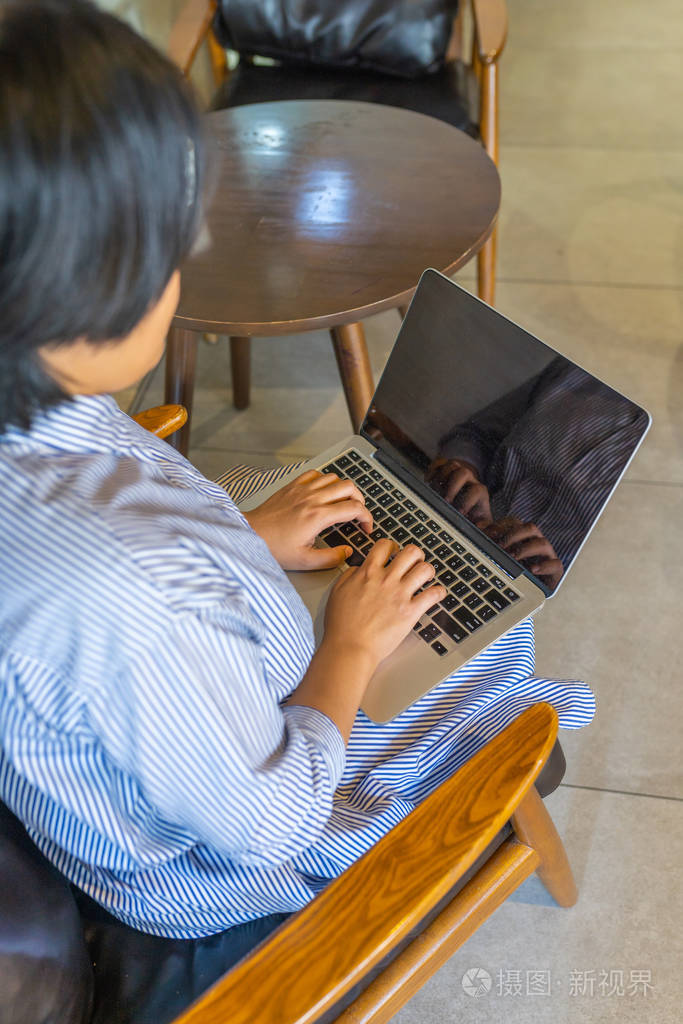 Asian businesswoman putting laptop on thigh and typing 